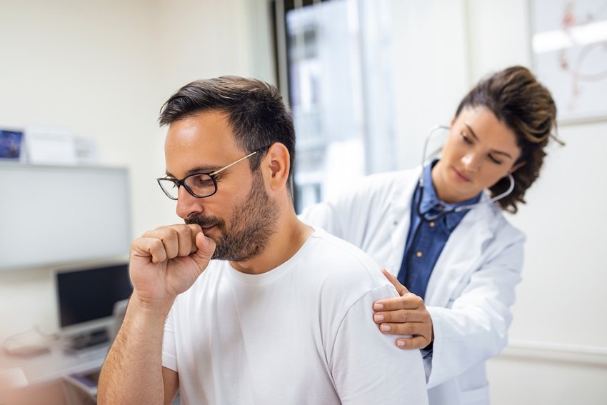 A female doctor at the clinic performs auscultation of the lungs of a patient with symptoms of coronavirus or pneumonia