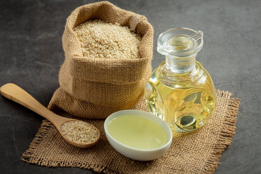 Sesame oil and sesame seeds on dark background
