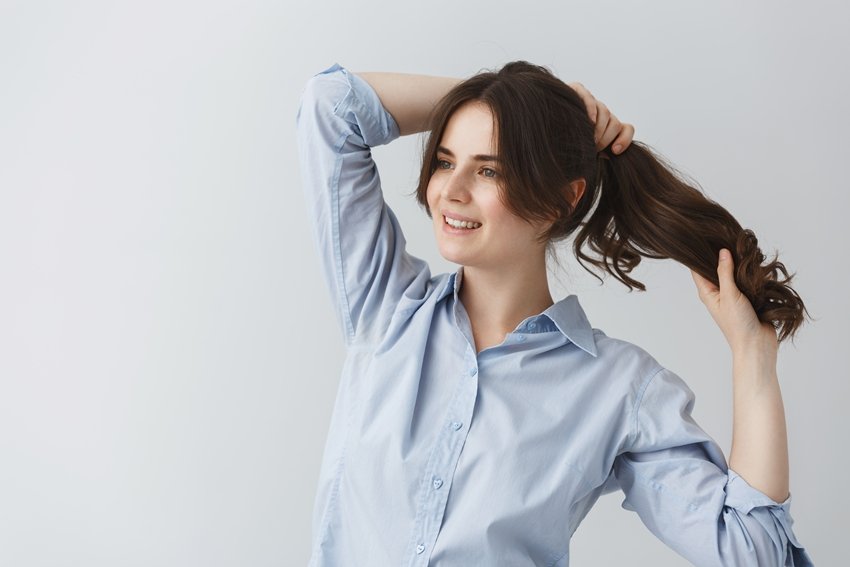 Young good-looking caucasian girl making hairstyle, getting ready for going out early in the morning with happy face expression.