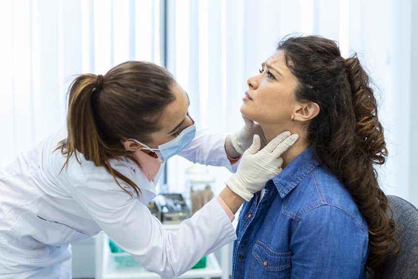 Endocrinologist examining throat of young woman in clinic. Women with thyroid gland test . Endocrinology, hormones and treatment. Inflammation of the sore throat