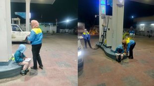 A young boy studying under the lights of a petrol pump while his mother works.