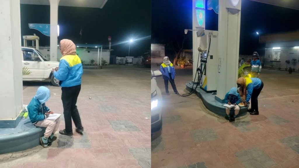 A young boy studying under the lights of a petrol pump while his mother works.