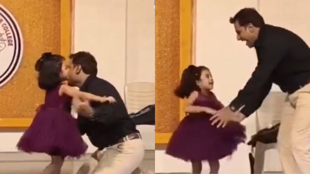 एक पिता अपनी छोटी बेटी के साथ स्कूल के स्टेज पर डांस करते हुए, आसपास के लोग ताली बजा रहे हैं। एक पिता अपनी छोटी बेटी के साथ स्कूल के स्टेज पर डांस करते हुए, आसपास के लोग ताली बजा रहे हैं।
